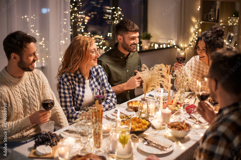 holidays, celebration and people concept - happy friends having christmas dinner at home drinking non-alcoholic red wine
