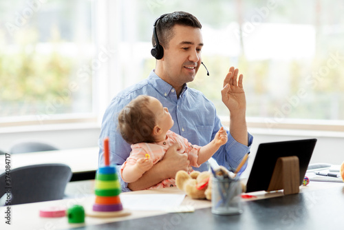 remote job, multi-tasking and family concept - middle-aged father in headset with baby having video conference on tablet pc computer at home office