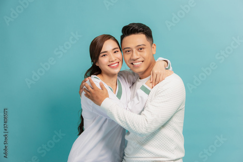 Happy couple embracing and looking camera on blue background