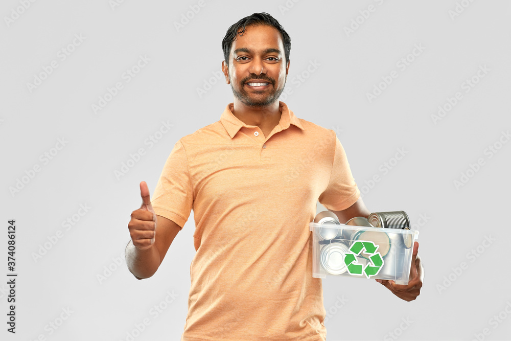 metal recycling, waste sorting and sustainability concept - smiling young indian man holding plastic box with tin cans showing thumbs up over grey background metal recycling, waste sorting and sustainability concept - smiling young indian man holding plastic box with tin cans showing thumbs up over grey background