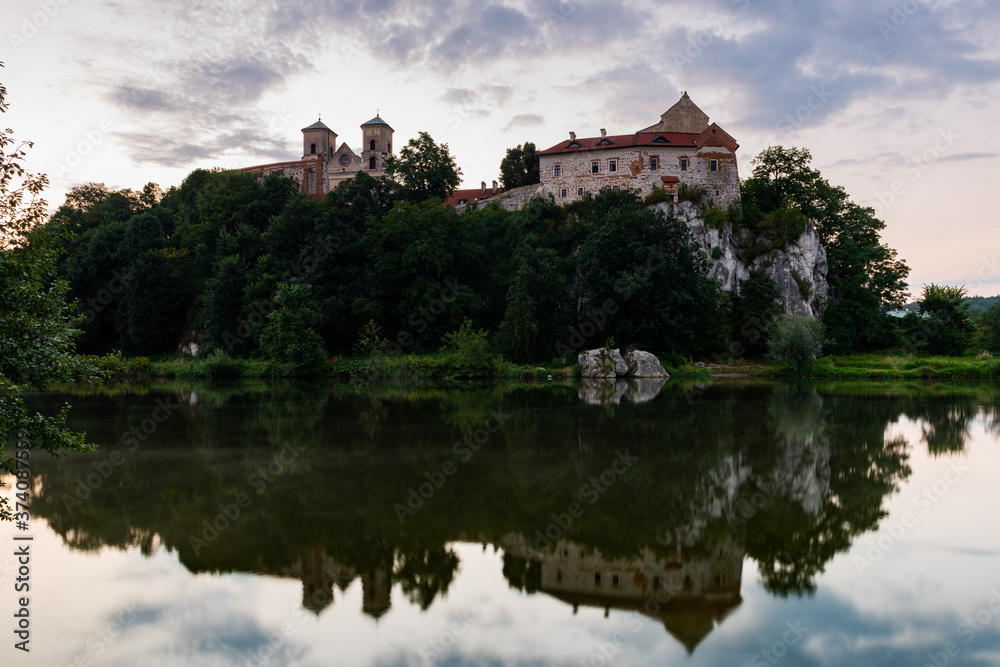 Picturesque Tyniec near Krakow, Poland. Benedictine Abbey, Monastery and Church on the Cliff . Clouds Reflection in Vistula River at Sunrise