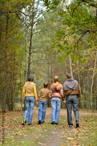 Family of four walking in autumn forest