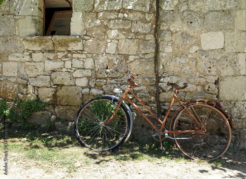 old abandoned bike leaning against a stone wall