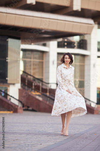 Beautiful smiling  middle age woman in the dress walking at the city street on a sunny day. © fadzeyeva