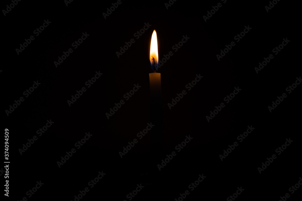 Close Up Single Burning, Bright White Paraffin Candle Light On Isolated Dark Black Background. Red, orange, yellow candle fire flame smoke in party festival celebration at night. Copy Space For Text. Close Up Single Burning, Bright White Paraffin Candle Light On Isolated Dark Black Background. Red, orange, yellow candle fire flame smoke in party festival celebration at night. Copy Space For Text.