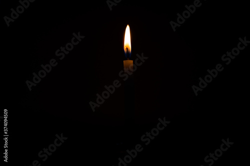 Close Up Single Burning, Bright White Paraffin Candle Light On Isolated Dark Black Background. Red, orange, yellow candle fire flame smoke in party festival celebration at night. Copy Space For Text.