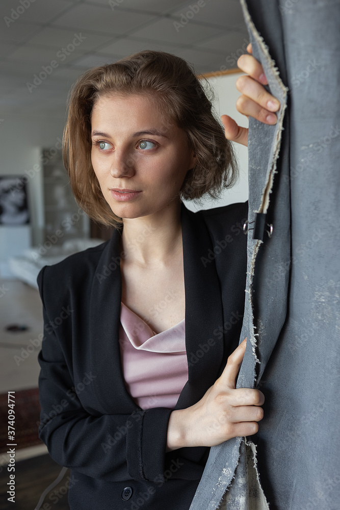 portrait of young caucasian woman with short hair posing in black suit jacket, holding curtain or fabric studio background. model tests of pretty girl, closeup. short-haired attractive female poses
