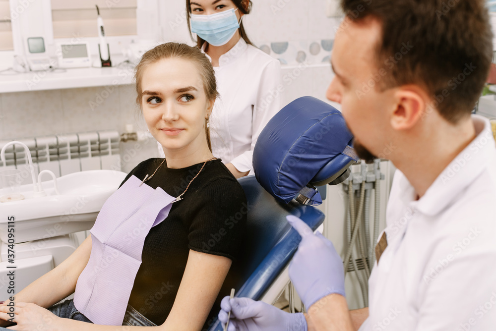 Dentist talking to a patient. Nearby is the dentists assistant. Reception in the dentists office and dental treatment Dentist talking to a patient. Nearby is the dentists assistant. Reception in the dentists office and dental treatment