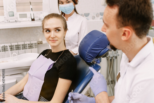 Dentist talking to a patient. Nearby is the dentists assistant. Reception in the dentists office and dental treatment