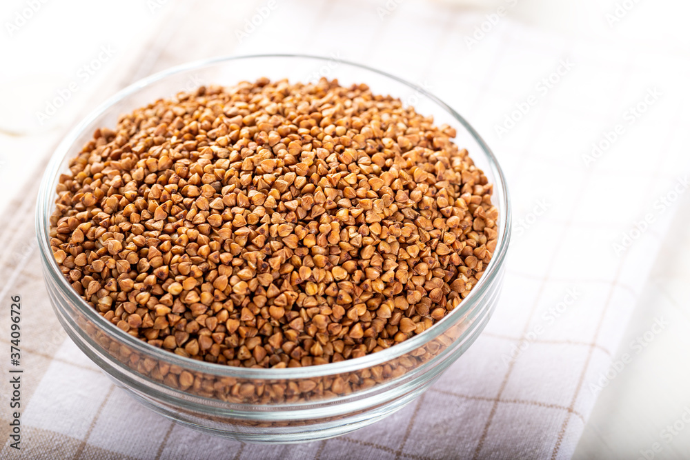 Bowl of raw buckwheat on wooden background. Buckwheat groats (hulled seeds) in bowl. Bowl of raw buckwheat on wooden background. Buckwheat groats (hulled seeds) in bowl.