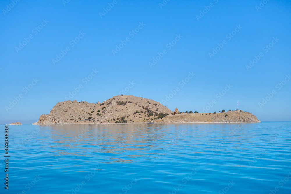 Akdamar island on Van Lake, Gevaş, Turkey. Right part of island is Cathedral of the Holy Cross & remains of monastery. Bright blue color of lake water is created by saline soda elements in its consist Akdamar island on Van Lake, Gevaş, Turkey. Right part of island is Cathedral of the Holy Cross & remains of monastery. Bright blue color of lake water is created by saline soda elements in its consist