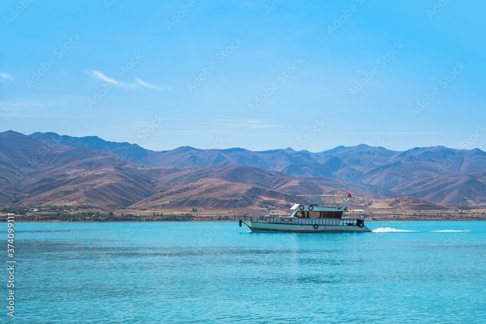 Tourist boat sailing across Van Lake. Mountains are on background. Picture taken from coast of Akdamar island, Gevaş Turkey. Island popular for its medieval Armenian Cathedral of Holy Cross