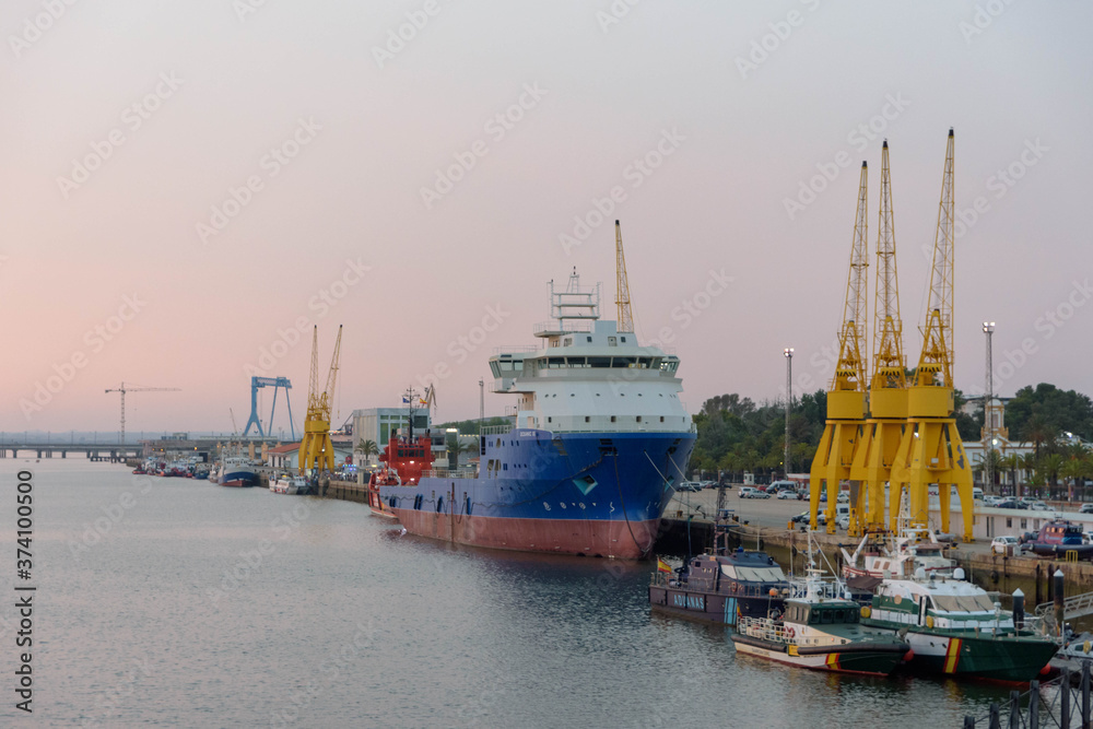 Port of Huelva at sunset with boats and cranes. Huelva, Andalusia, Spain