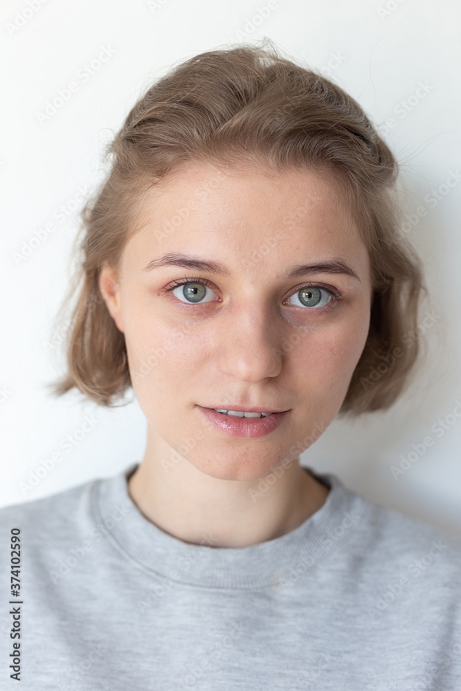 portrait of caucasian woman with clean skin, short hair posing in gray sweatshirt on white background, looking at camera. model tests of pretty girl in basic clothes, close up. attractive female poses portrait of caucasian woman with clean skin, short hair posing in gray sweatshirt on white background, looking at camera. model tests of pretty girl in basic clothes, close up. attractive female poses