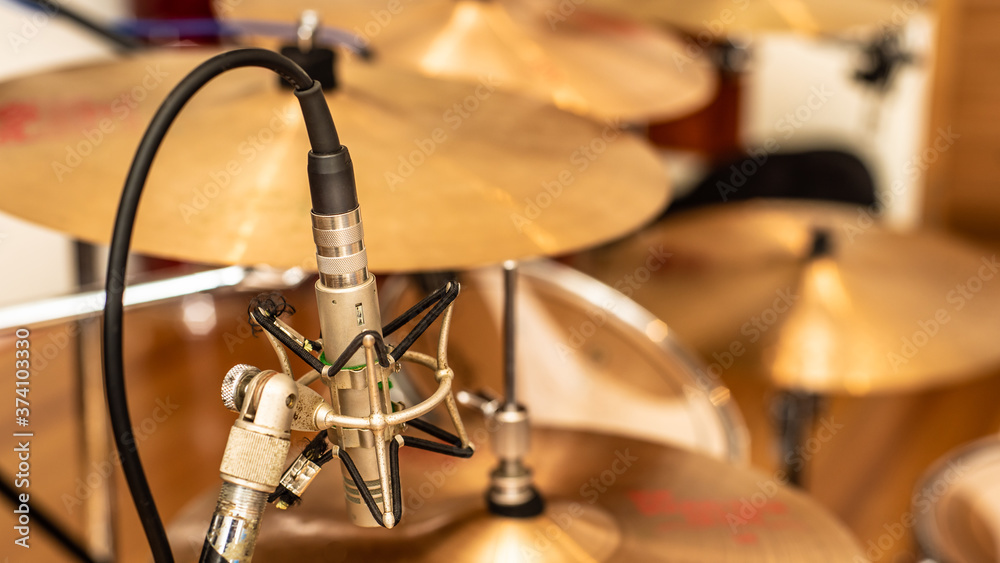 A vintage pencil microphone in place for recording drums in a recording studio setting