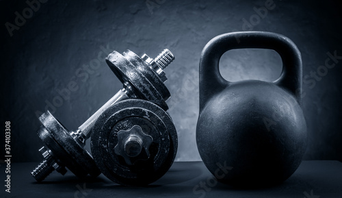 Sports dumbbells and kettlebell on a dark background
