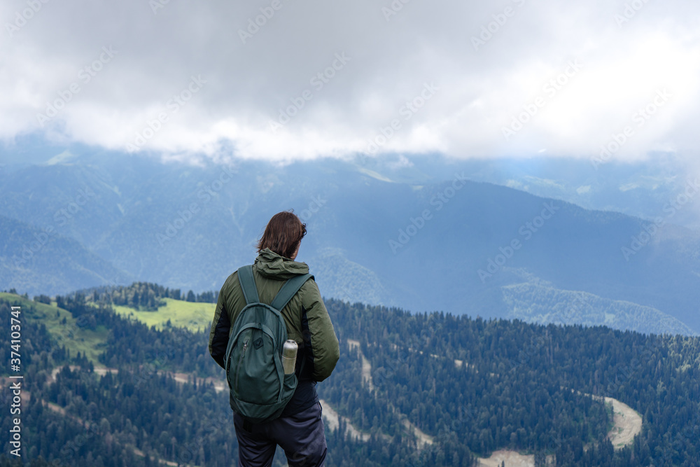 oung hiker stand in beautiful mountains on hiking trip. Active person resting outdoors in  nature. Backpacker camping outside recreation active