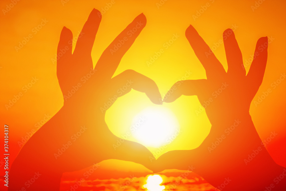 Fingers in the form of a heart on the background of a beautiful sunset Fingers in the form of a heart on the background of a beautiful sunset