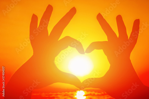 Fingers in the form of a heart on the background of a beautiful sunset
