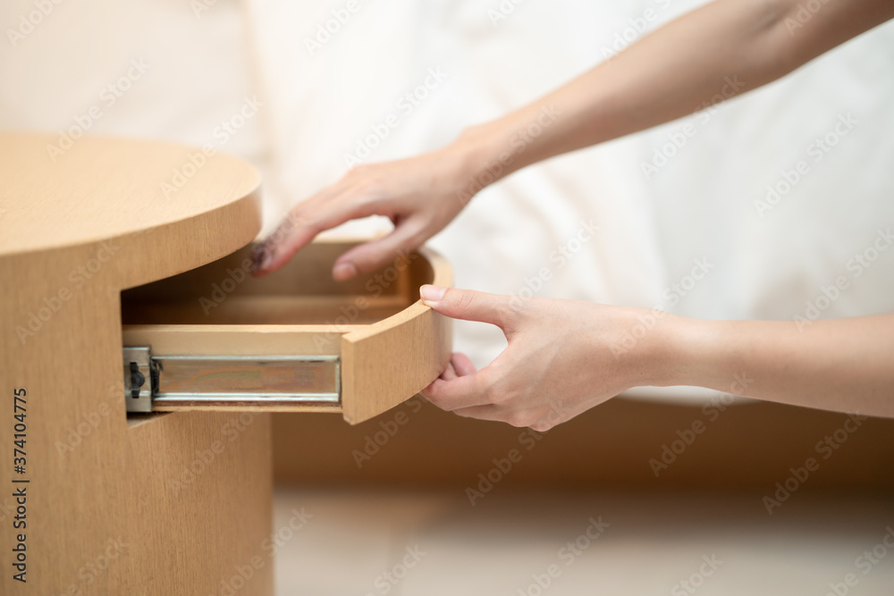 Obraz premium Woman hand opening a drawer in the wooden table.