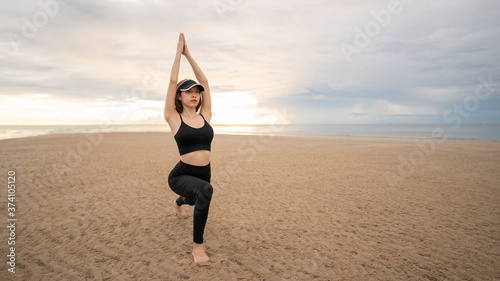 Woman doing yoga asana low lunge on the beach with sunrise on the morning.