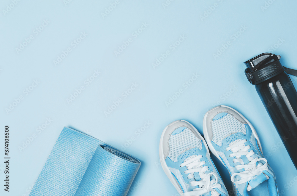 Yoga mat, sport shoes, bottle of water on blue background. Healthy lifestyle Yoga mat, sport shoes, bottle of water on blue background. Healthy lifestyle