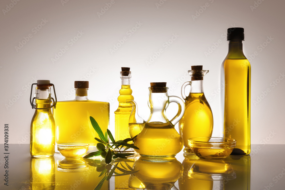 Assorted glass containers with olive oil backlit on glass table Assorted glass containers with olive oil backlit on glass table