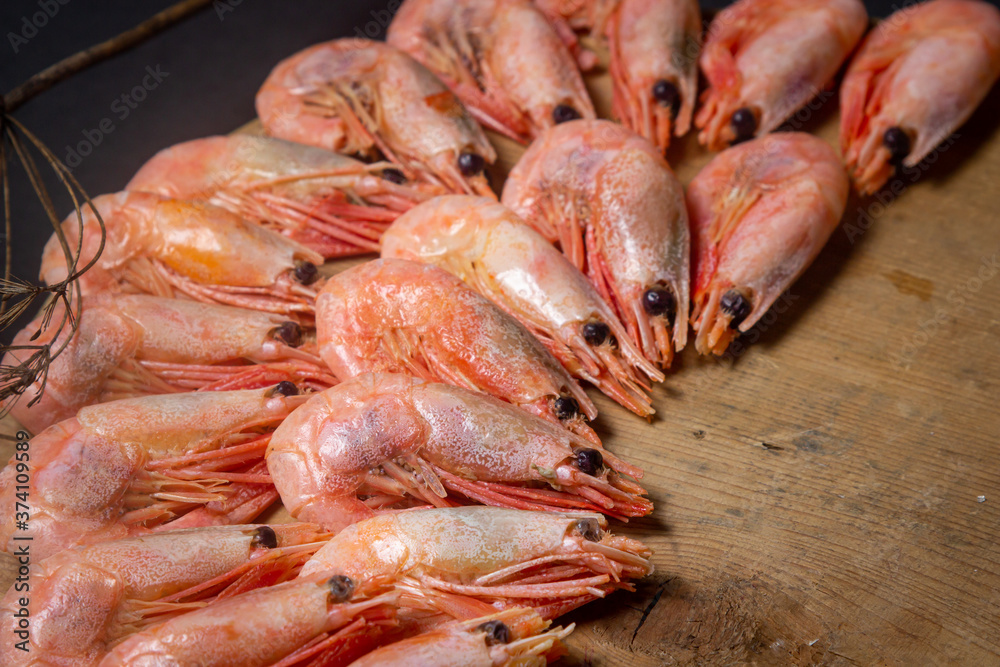 Boiled shrimp. Shrimps lie on a wooden board. Decorated around with dry greenery. Seafood