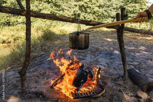 Camping, a pot of water boils over the fire.