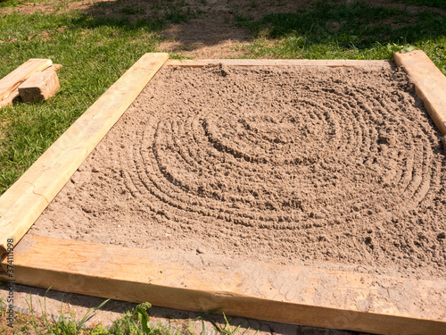 Tablou pe pânză Homemade children sandbox with wooden sides and circles on sand side view