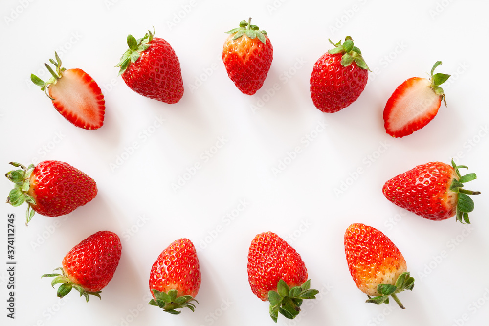 Oval frame of whole and halved strawberries on white background. Isolated. Copy space. Oval frame of whole and halved strawberries on white background. Isolated. Copy space.