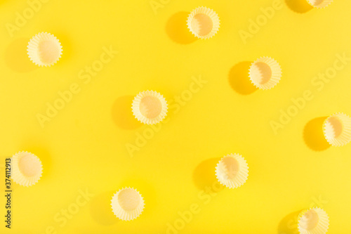 Trendy pattern made with yellow cap on bright yellow background. Minimal concept.