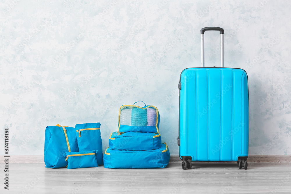 Obraz premium Set of travel organizers with belongings and suitcase on floor at home