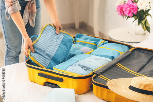 Obraz na plátně Woman packing clothes before journey at home