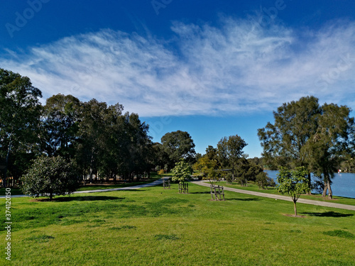 Beautiful view of a park with green grass, tall trees and paved trail for walking and cycling, Reid Park, Parramatta Cycleway, Rydalmere, Sydney, New South Wales, Australia 