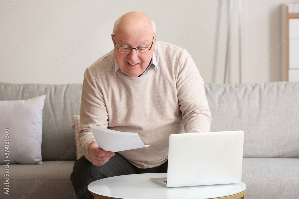 Senior man calculating expenses at home