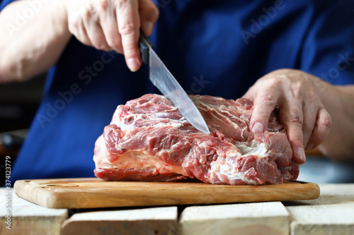 Selective focus. The chef cuts raw meat on the board. Pork neck. Cooking pork.
