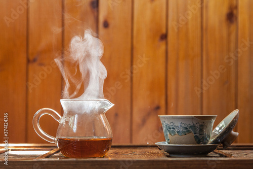Chinese tea cup and glass kettle  with cloud of vapor on wooden background