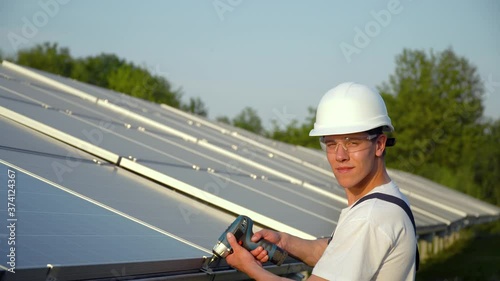 Wallpaper Mural Worker in a uniform and hardhat installing photovoltaic panels on a solar farm. Concept renewable energy Torontodigital.ca