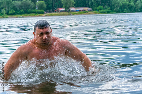 A man emerges from under the water, swimming in a cool river in summer © Николай Чекалин