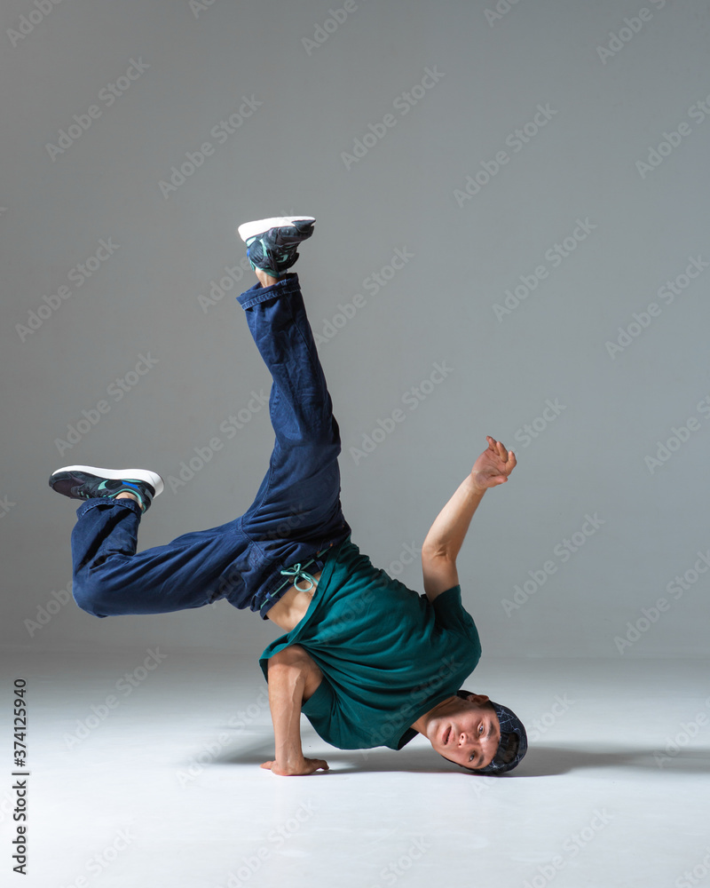 Foto Stock Cool guy breakdancer dancing on one hand isolated on gray  background. Breakdance poster | Adobe Stock