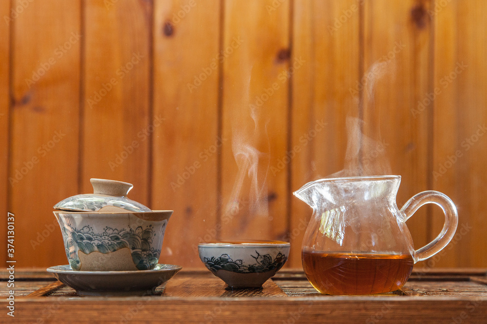 Chinese tea cup and glass kettle with cloud of vapor on wooden background Chinese tea cup and glass kettle with cloud of vapor on wooden background