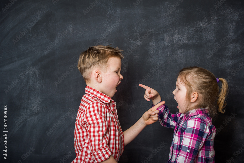 Boy and girl pointing fingers to each other. Raging kids children