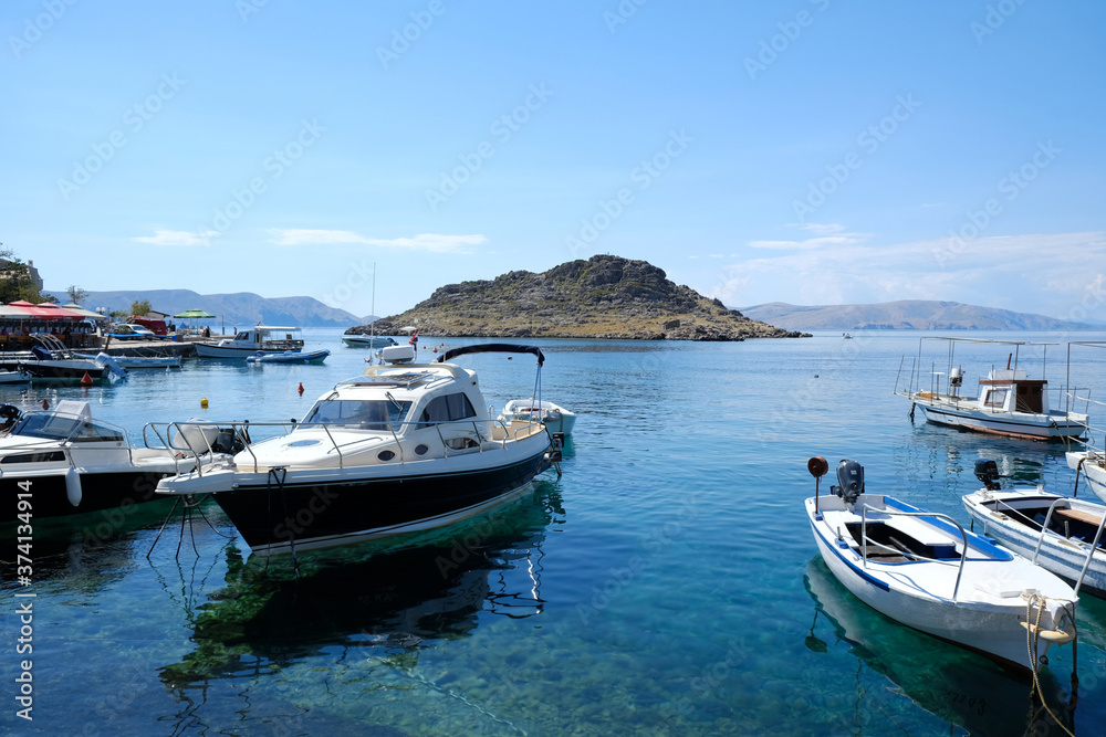 Boats are standing on amazing crystal clear water in marina. Island on horizon. Adriatic, Sveti Juraj, Croatia. 