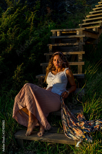 Chica joven posando en unas escaleras de madera al tardecer en la playa photo