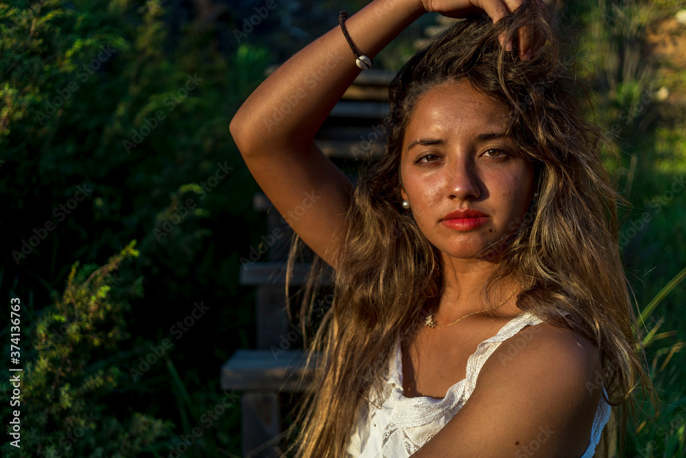 Chica joven posando en unas escaleras de madera al tardecer en la playa Chica joven posando en unas escaleras de madera al tardecer en la playa
