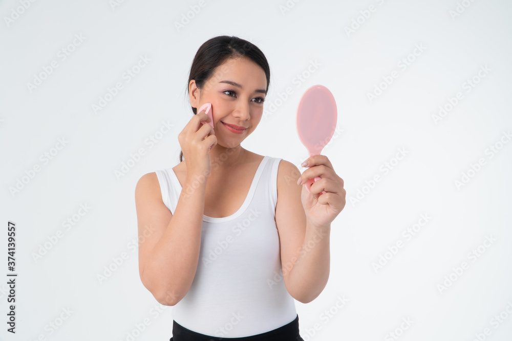 Beautiful young Asian woman cleaning her skin with a cotton pad and holding Makeup mirror, isolated over white background Beautiful young Asian woman cleaning her skin with a cotton pad and holding Makeup mirror, isolated over white background
