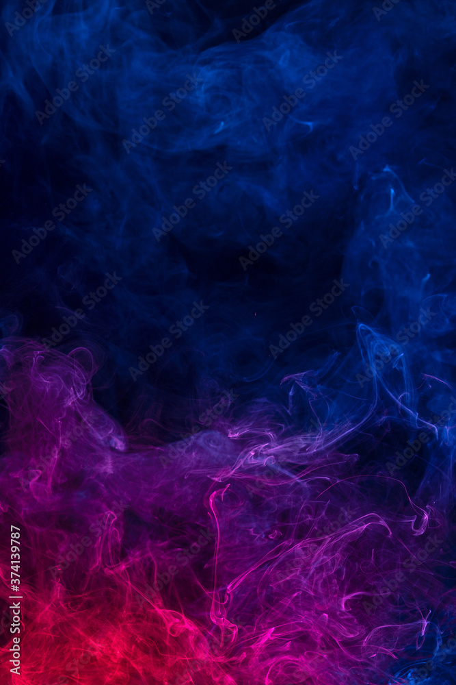 Conceptual image of multi-colored smoke isolated on dark black background, Halloween design element.