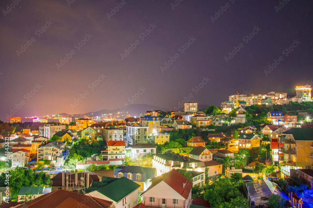 View of the resort town with many houses near the sea in the distance in the mountains night lights.