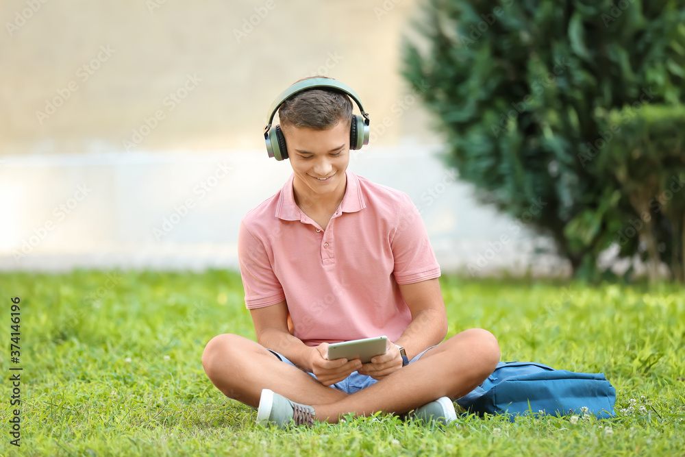 Fototapeta premium Teenage boy listening to music in park